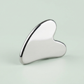 Silver Gua Sha tool on a light gray background